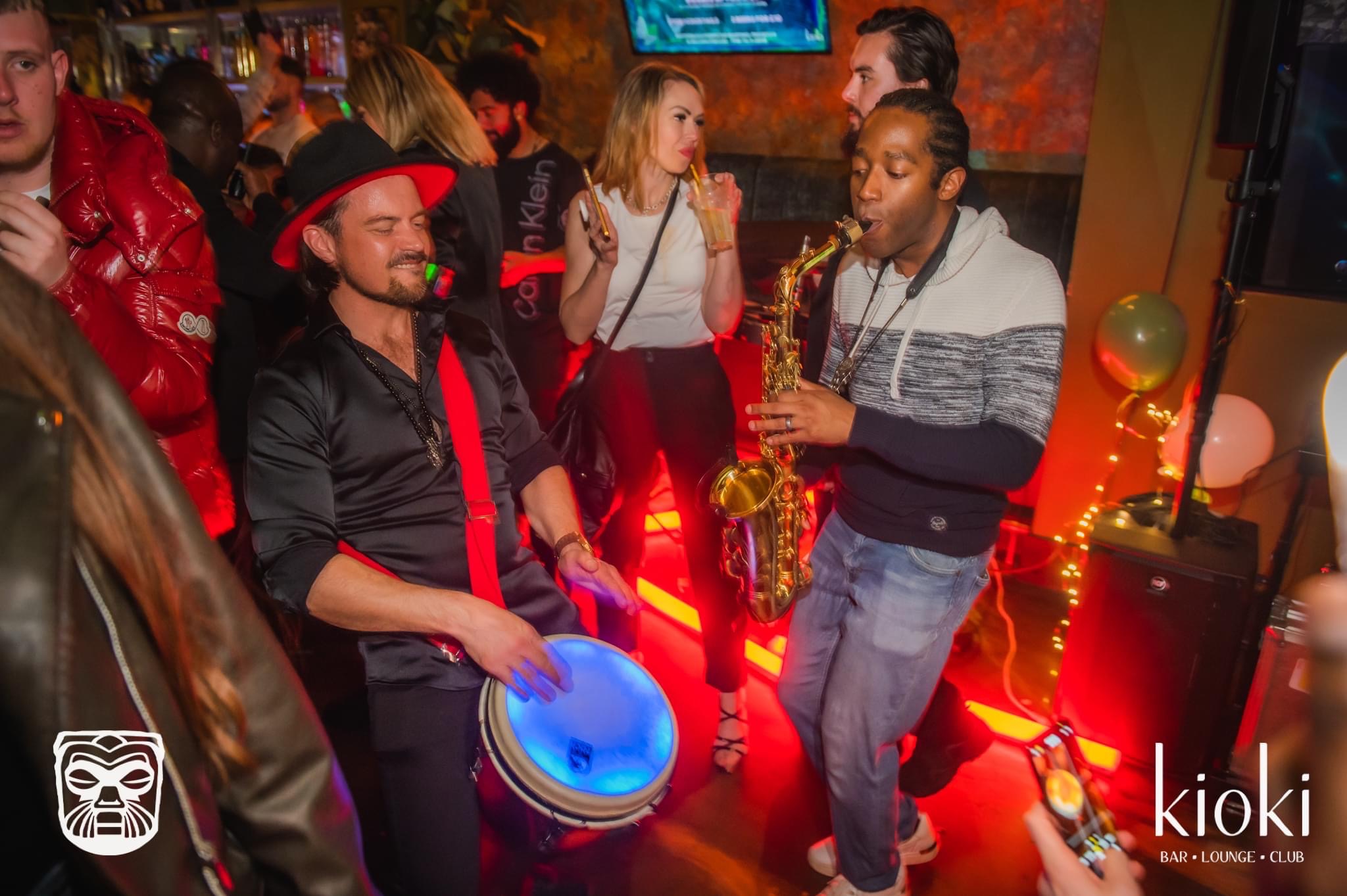 Devin playing saxophone with a percussionist in a nightclub